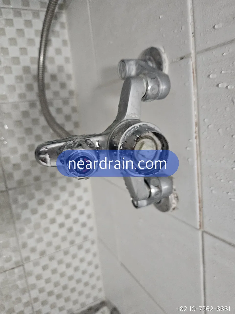 Shower mixer valve body opened on a tiled bathroom wall