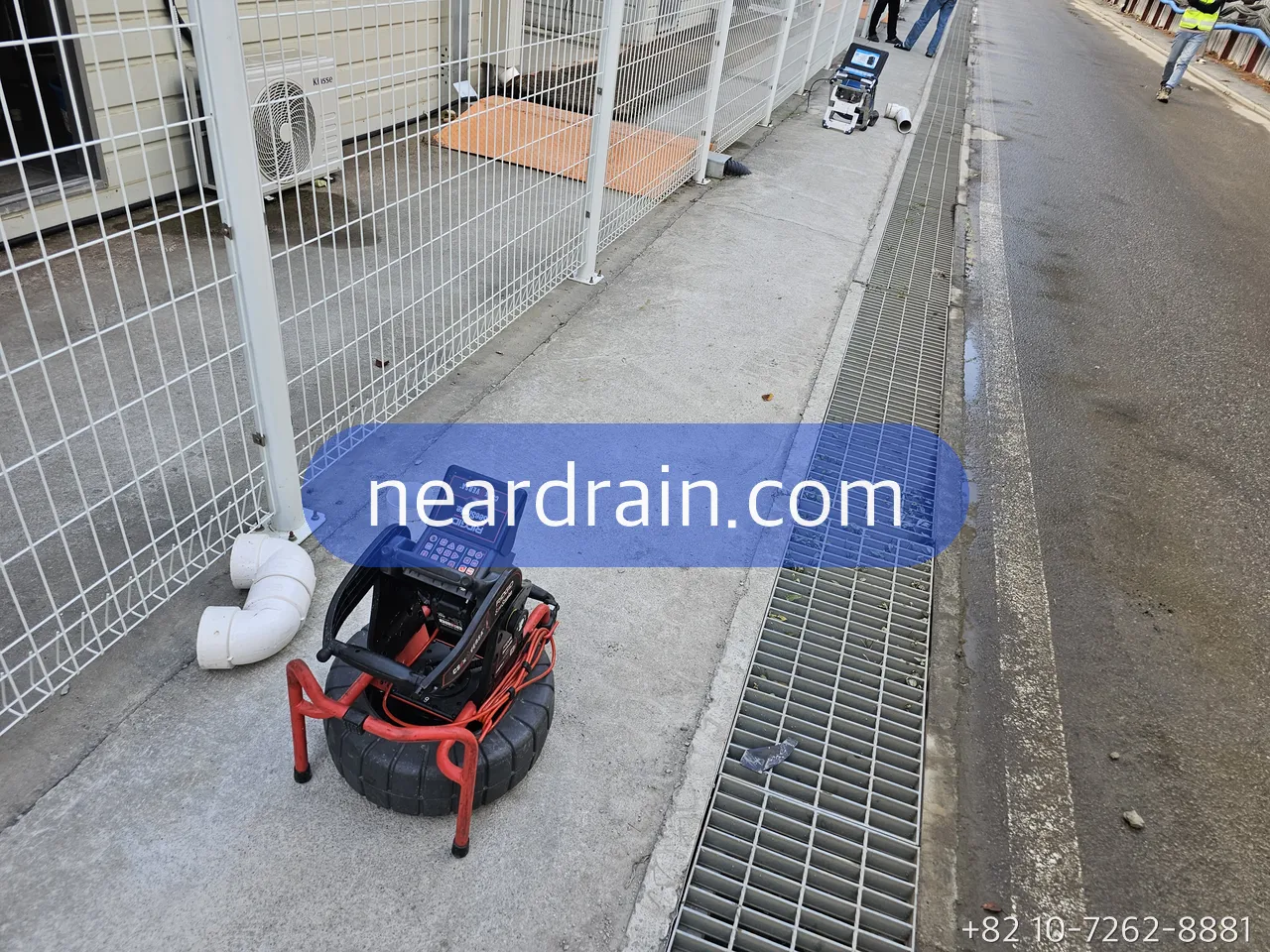 Drain camera reel set beside a trench drain after jetting for the verification pass