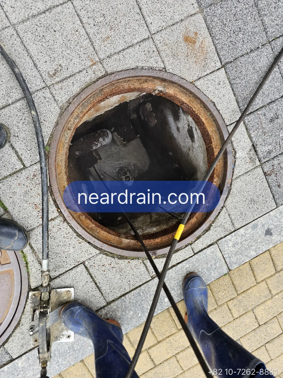 Jetting hose run into a sidewalk manhole