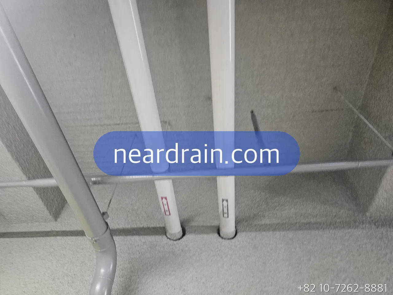 White supply pipes rising through a concrete utility shaft in an apartment building, isolation valves on each branch