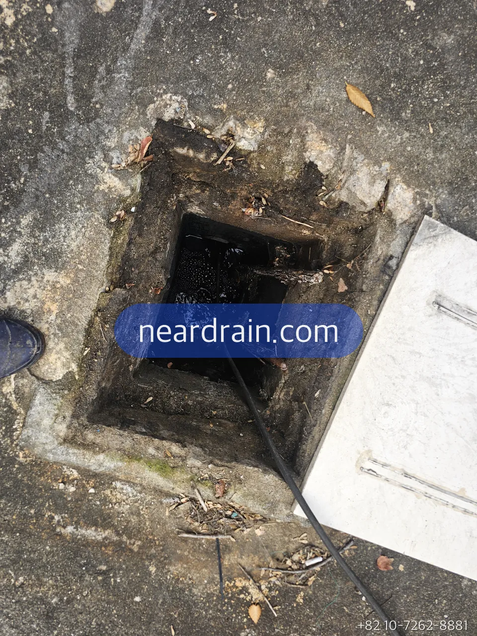 Square lift pit in a basement floor with the cover lifted off