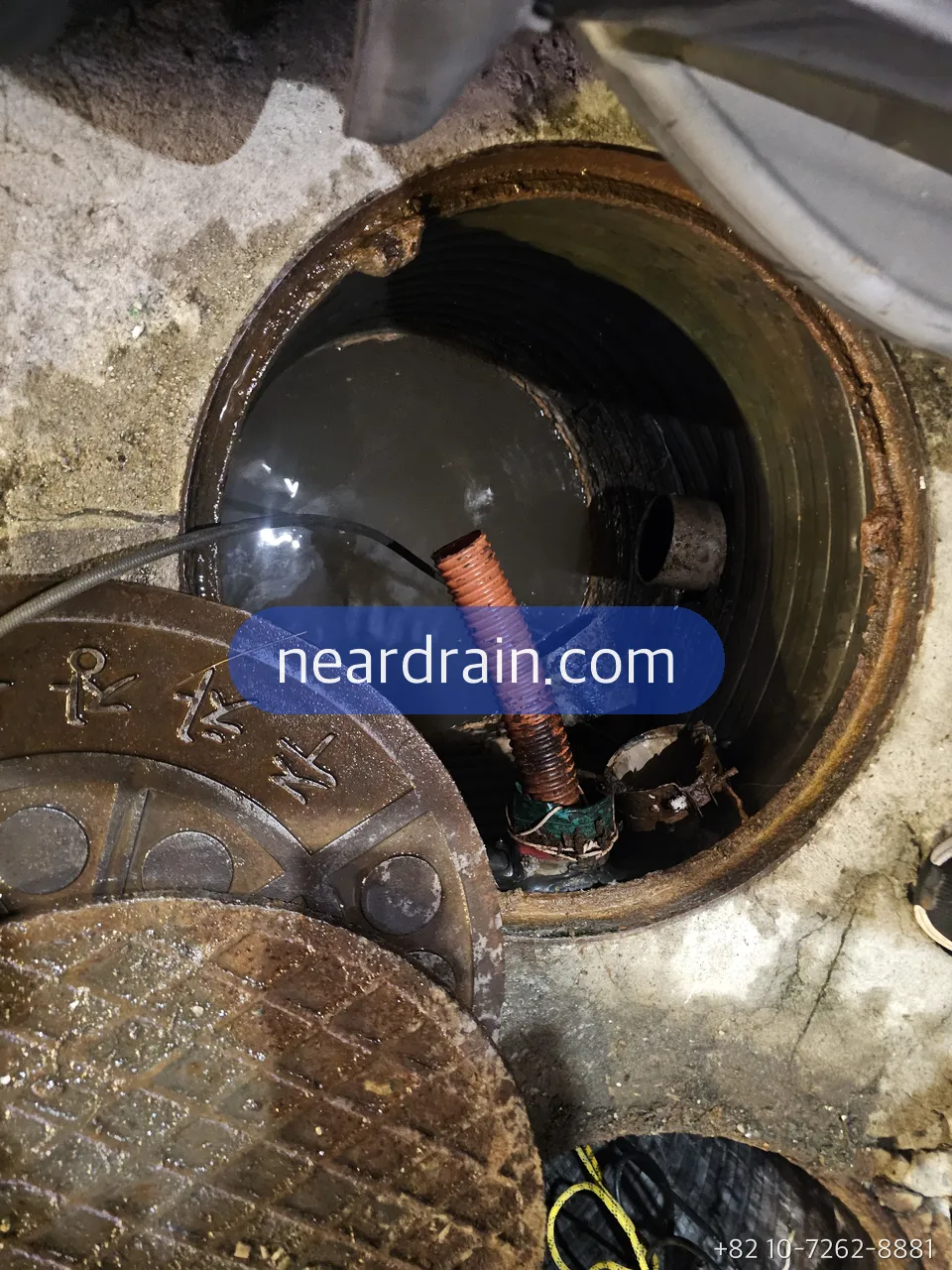 Basement shop sewage pit hatch open at night with discharge hose in place
