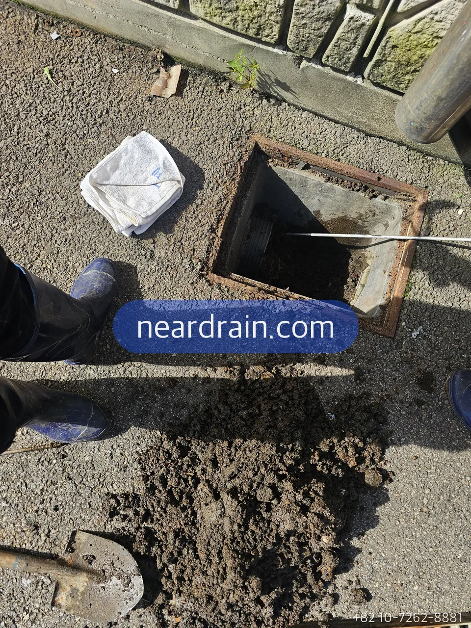 Silt shoveled out of a rain gully onto the pavement beside the open box