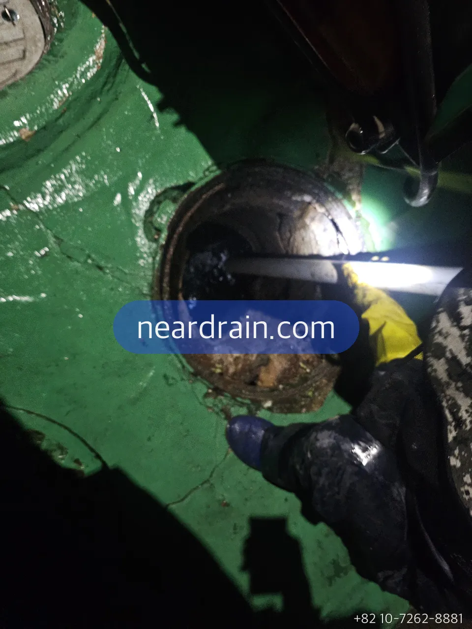 Roof drain on a green waterproofed rooftop opened with a cable being fed into the downpipe