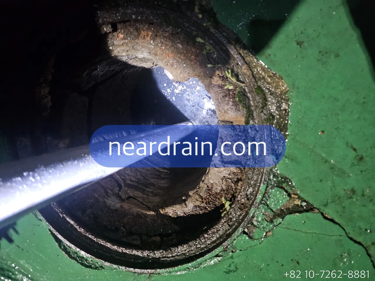 Jetting nozzle held at an opened roof drain on a green rooftop membrane