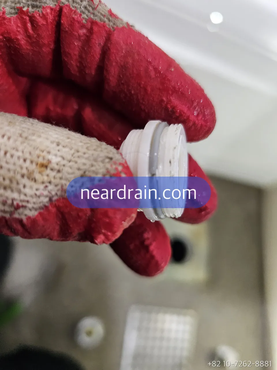 Scaled eccentric adapter removed from a shower mixer, held in a gloved hand