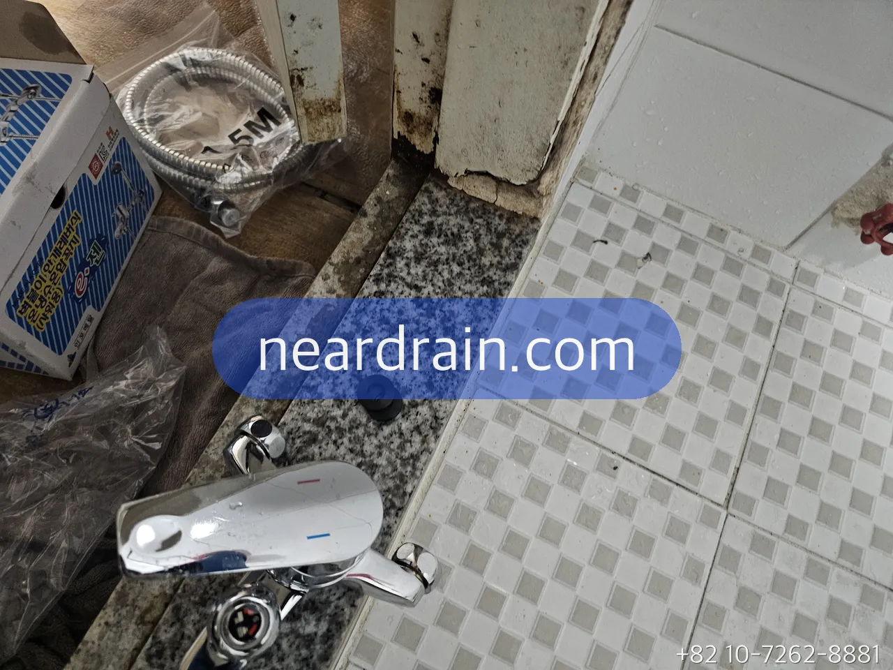 Old wall shower faucet removed and lying on a bathroom counter beside a boxed replacement hose, corroded wall outlets behind