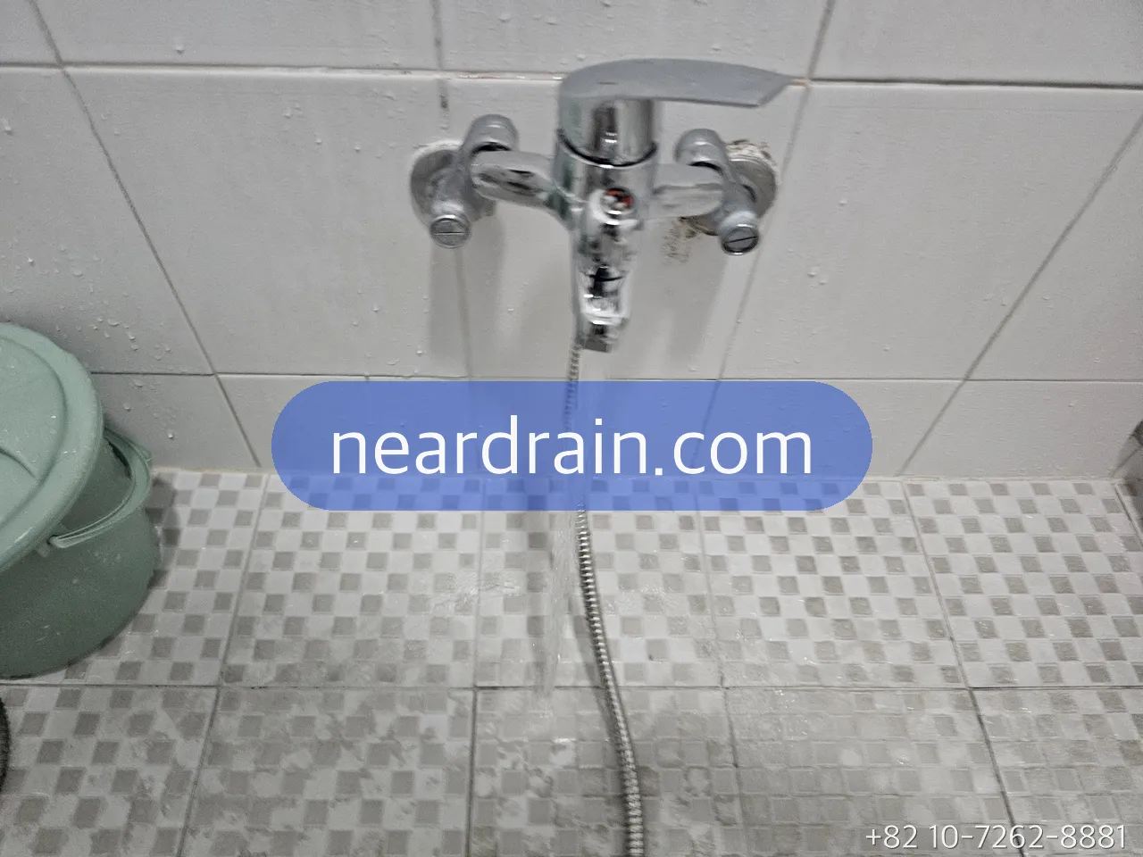 Chrome wall-mounted Korean shower mixer with a single lever on white tile, hand shower hose hanging to the floor