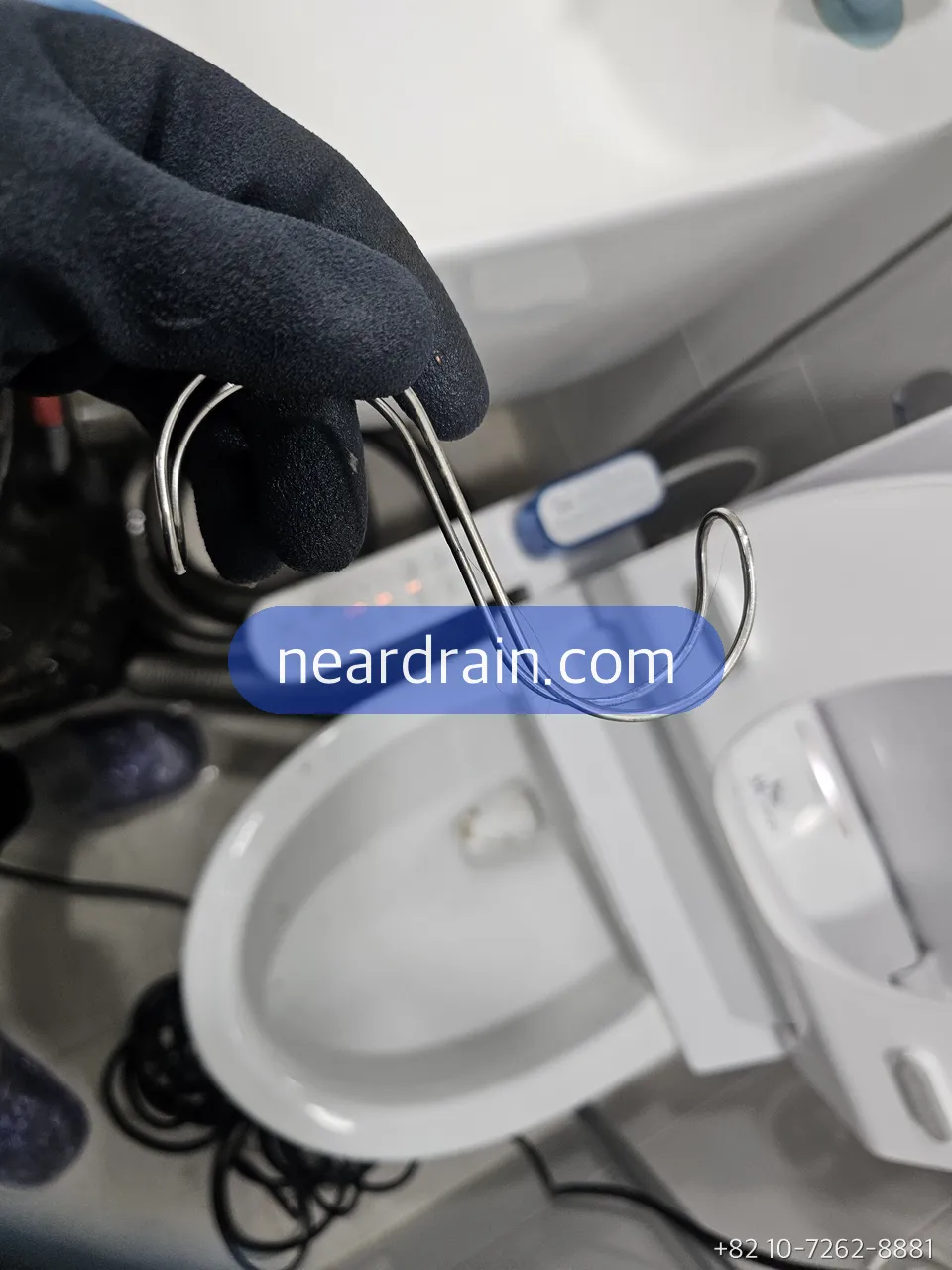Bidet supply hose and T-valve checked at the wall behind a toilet
