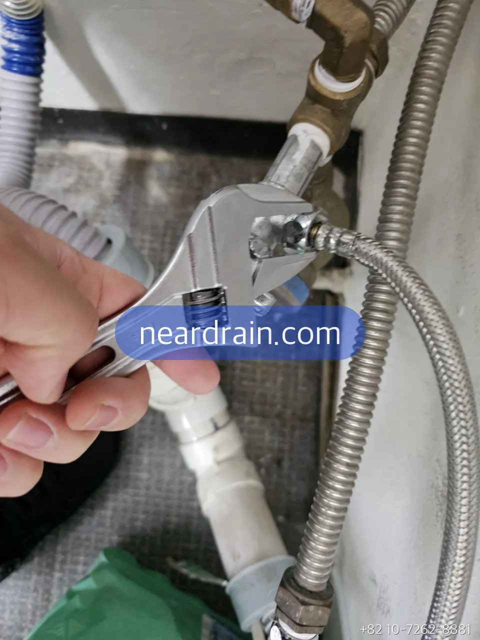 Adjustable wrench tightening the nut on a braided toilet supply hose at the angle valve