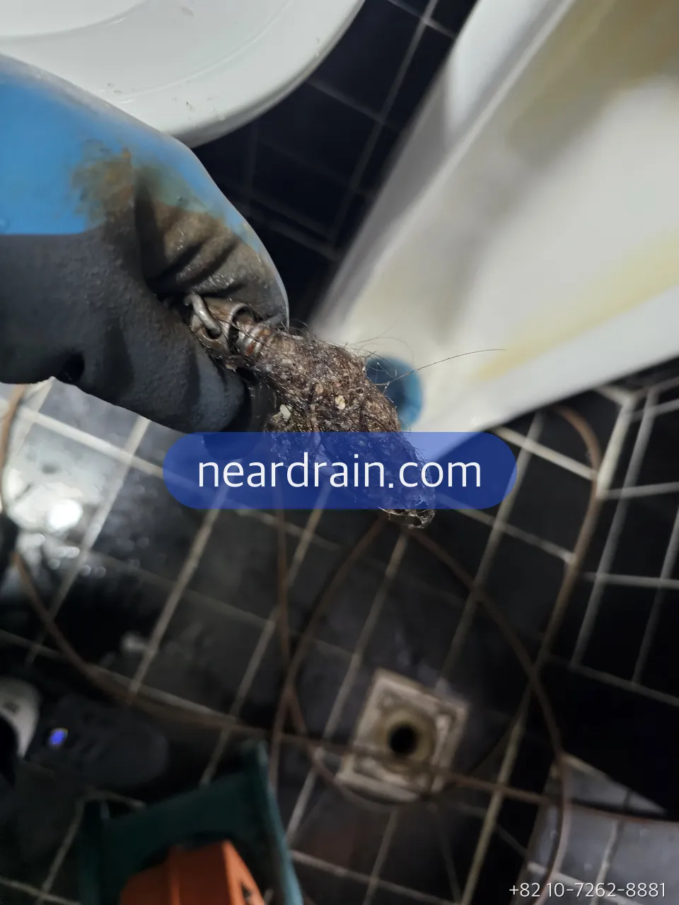 Gloved hand holding a rope of wet wipes pulled from a toilet line with a hook